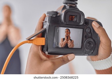 Close up of photographer holding camera with portrait of Black young woman on screen during photoshoot in studio, copy space - Powered by Shutterstock