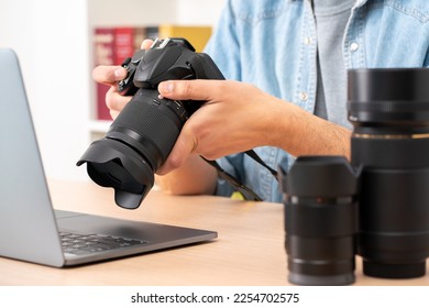 Close up of photographer man hands with laptop checking dslr camera on a desk at home - Shutterstock ID 2254702575