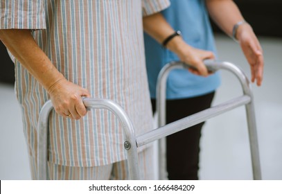 close up  physical therapist helping senior patient in using walker - Powered by Shutterstock