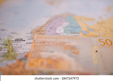Close up picture of a blurry fifty Swedish kronor banknote -with the words Fifty Kronor in Swedish- below Sweden on a colorful map of Europe with the rest of the countries blurred out