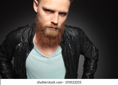 Close Up Picture Of A Casual Young Man With A Long Beard Looking Into The Camera. On A Dark Studio Background