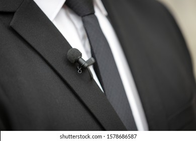 Close Up Picture Of A  Clip On Microphone On A Black Suit