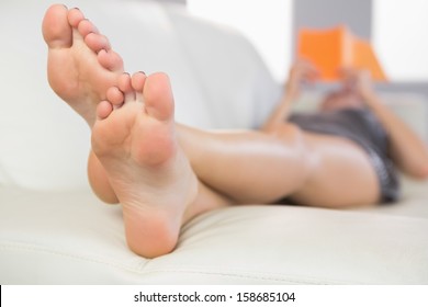 Close Up Picture Of Feet From Woman Lying On Couch In Bright Living Room