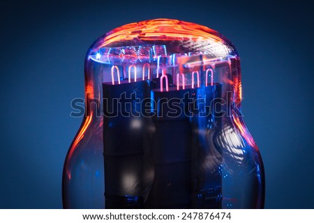 Close up picture of filaments of electronic vacuum tube rectifier. Blue and black background