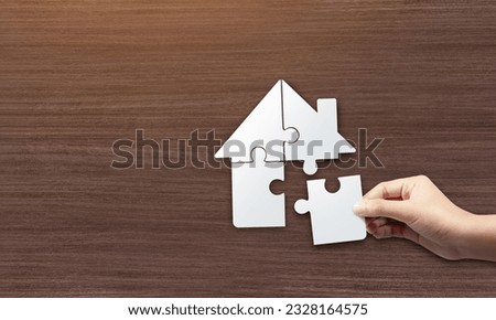 Close up picture of hands holding house jigsaw puzzle. build a house concept.
