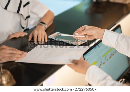 Close up picture of hands passing documents on a reception desk