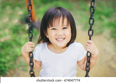 Close Up Picture Of Happy Face Kid Who Playing Swing.Free Play In The Playground For Baby And Toddler Is Important Activity For Child Development.