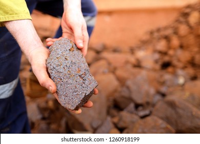 Close up picture of scientist geologist hands inspecting exploration on iron ore rock on open field mine site, Perth, Australia 
