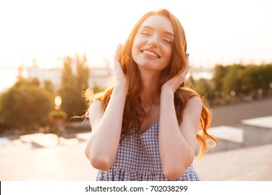 Close Up Picture Of Smiling Beauty Ginger Woman In Dress Listening Music With Closed Eyes On The Sunset