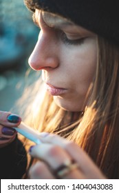 Close up picture of a young lady rolling a Tabasco cigarette by her self. Making a Rollie. Bad habits, lung problems. Sunny weather, sitting outside, serious and Moodie picture. warm desaturated color - Shutterstock ID 1404043088