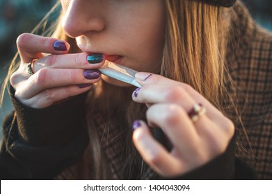 Close up picture of a young lady rolling a Tabasco cigarette by her self. Making a Rollie. Bad habits, lung problems. Sunny weather, sitting outside, serious and Moodie picture. warm desaturated color - Shutterstock ID 1404043094