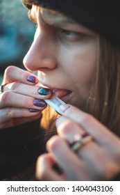 Close up picture of a young lady rolling a Tabasco cigarette by her self. Making a Rollie. Bad habits, lung problems. Sunny weather, sitting outside, serious and Moodie picture. warm desaturated color - Shutterstock ID 1404043106