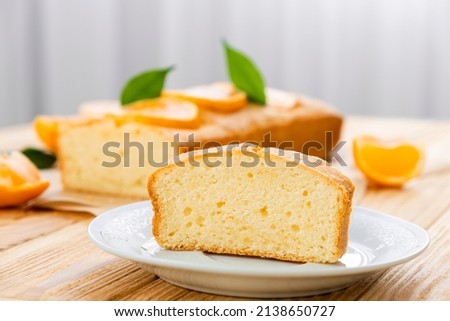 Close up piece of moist orange fruit pound cake on plate with slices of orange and whole pie on background. Delicious breakfast, traditional English tea time. Recipe of orange pie loaf. Stock photo © 