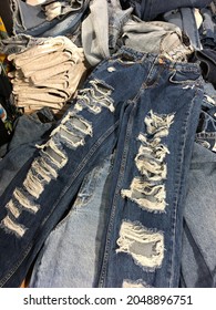 Close Up Pile Of Blue Jean With A Hole And Threads With Khaki Pants 

