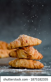 Close up of pile of delicious croissants on a dark background. Homemade croissants. Sugar glass falling. Vertical.
					
