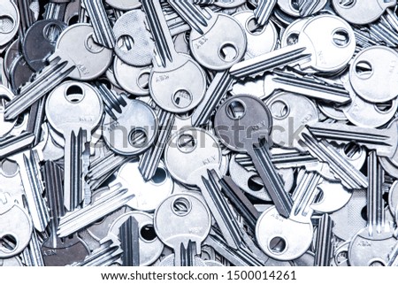 Close up of a pile of keys. Gray industrial background.