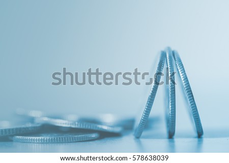 Close up of pile of silver  coins over soft background in blue tone with copy space for finance business and banking concept