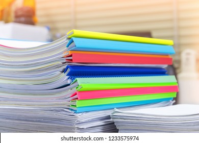 Close up pile of unfinished homework assignment stacked in archive with colorful plastic slide binder bars waiting to be managed and inspected. Stack of paperwork. Education and business concept. - Shutterstock ID 1233575974