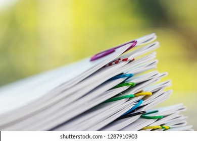 Close up pile of unfinished homework assignment stacked in archive with colorful paper clips on table in school waiting to be managed and inspected. Stack of paperwork. Education and business concept. - Shutterstock ID 1287910903