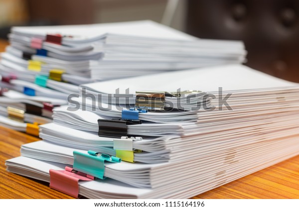 管理待ちのオフィスデスク上の未完了の書類の山を接写します 宿題の山とクリップ 書類を積み重ねる ビジネスと教育のコンセプト の写真素材 今すぐ編集