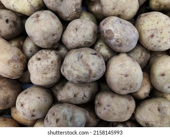 Close up of pile of unpeeled fresh potatoes at stall of supermarket in Asia. Cooking ingredient. Selective focus.