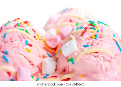close up of pink berry scoops ice cream strewed sprinkles, marshmallows and icing isolated on white background