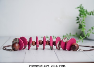 Close Up Of Pink Fabric Necklace With Coconut Shell Beads On White Wooden Table. Etnic Handmade Jewelery.