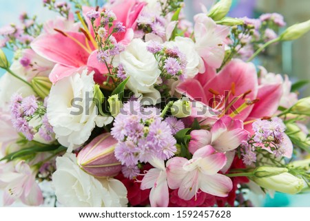 Close up of pink lily flowers around by roses, carnation flowers and green leaves. Close up of beautiful colorful bouquet of flowers with lily and roses. Different kind of flowers. Selective focus.