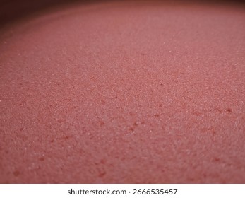 Close up of pink sponge texture with soft porous surface. Abstract background for design, cleaning, craft, or interior concept. Macro detail with vibrant color.
