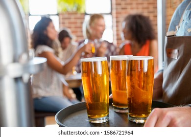 Cierre De Las Pintas De Cerveza Con Los Clientes Tomando En Segundo Plano Foto de stock