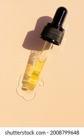 close up of pipette with pouring liquid serum and shadows on beige background. Trendy cosmetics shot with hard shadows. - Shutterstock ID 2008799648