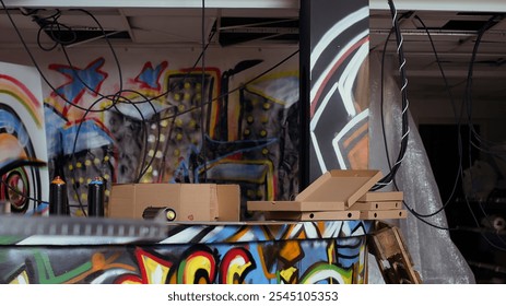 Close up of pizza boxes leftover by teenagers in city suburb abandoned building with graffiti art on walls. Vandalized location left in messy state by unlawful teens, concept of urban culture - Powered by Shutterstock