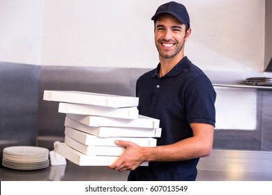 Close up of pizza delivery man carrying boxes in commercial kitchen - Powered by Shutterstock