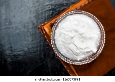 Close up of plain curd or yogurt or dahi in transparent glass bowl on a brown cloth or napkin on wooden surface.