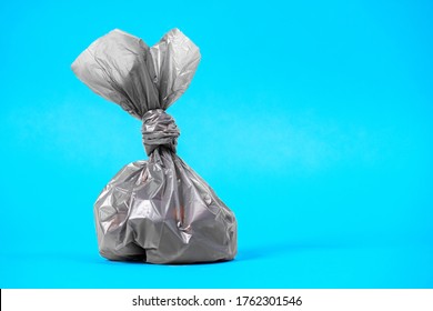 Close up plastic bag gathering with dog poop droppings on a blue background. Eco friendly solution for pet owners