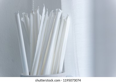 Close Up plastic straws with paper wrappers in cup container on blur white background