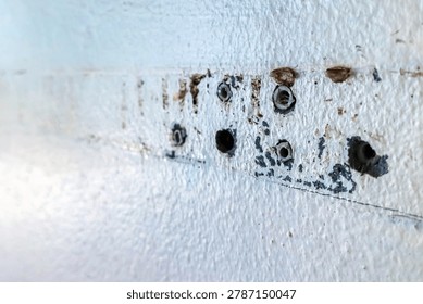 Close up of plastic wall plugs inside drilled holes on dirty concrete wall. Plastic dowels or wall anchors embedded into holes drilled in an old concrete wall. Home renovation and repair concept.