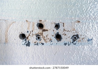 Close up of plastic wall plugs inside drilled holes on dirty concrete wall. Plastic dowels or wall anchors embedded into holes drilled in an old concrete wall. Home renovation and repair concept.