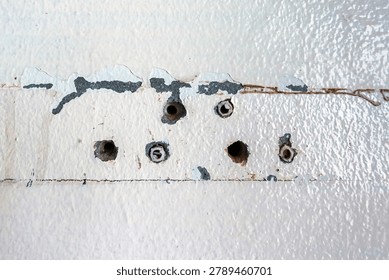 Close up of plastic wall plugs inside drilled holes on dirty concrete wall. Plastic dowels or wall anchors embedded into holes drilled in an old concrete wall. Home renovation and repair concept.