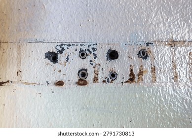 Close up of plastic wall plugs inside drilled holes on dirty concrete wall. Plastic dowels or wall anchors embedded into holes drilled in an old concrete wall. Home renovation and repair concept.