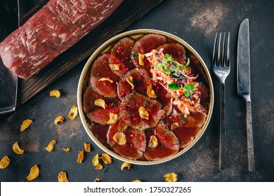 Close up plate of beef Tataki, sliced thinly beef served with a citrus soy dipping sauce, Kim chi cabbage. Decorated with rucola, onion and pomegranate seeds - Powered by Shutterstock