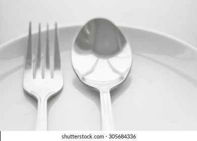 Close up plate isolate with spoon and fork on a wooden table . (Focus at fork and spoon )