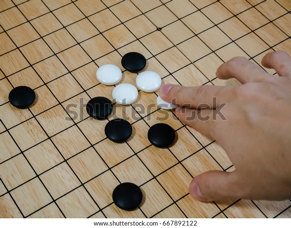 close up of player hand make a move\
in Go game(Weiqi),Traditional asian strategy board\
game