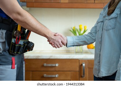 Close up of plumber and client shaking hands in kitchen. Repairman shaking hands with woman - Shutterstock ID 1944313384
