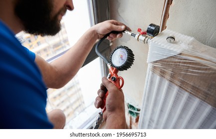 Close Up Of Plumber Filling Pipes With Pressurized Air To Inspect For Leaks In New Installation, Using Air Compressor While Checking Gas Tightness Of Heating System. Concept Of Home Renovation