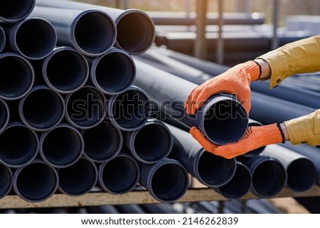 Close up plumber hands choosing a pipe for sewage on a construction site.
