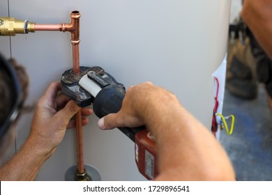 A Close Up Of A Plumber Installing An Electrical Hot Water Cylinder. 