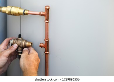 A Close Up Of A Plumber Installing An Electrical Hot Water Cylinder. 