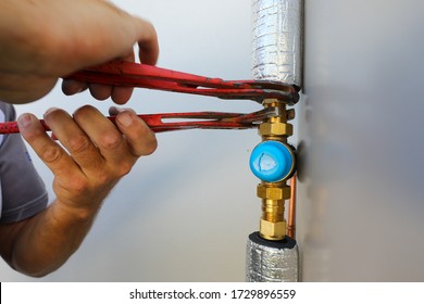 A close up of a plumber installing an electrical hot water cylinder. 