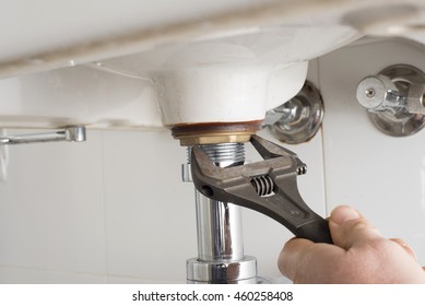 Close Up Of A Plumbers Wrench Tightening Leaky Pipe Under Bathroom Basin